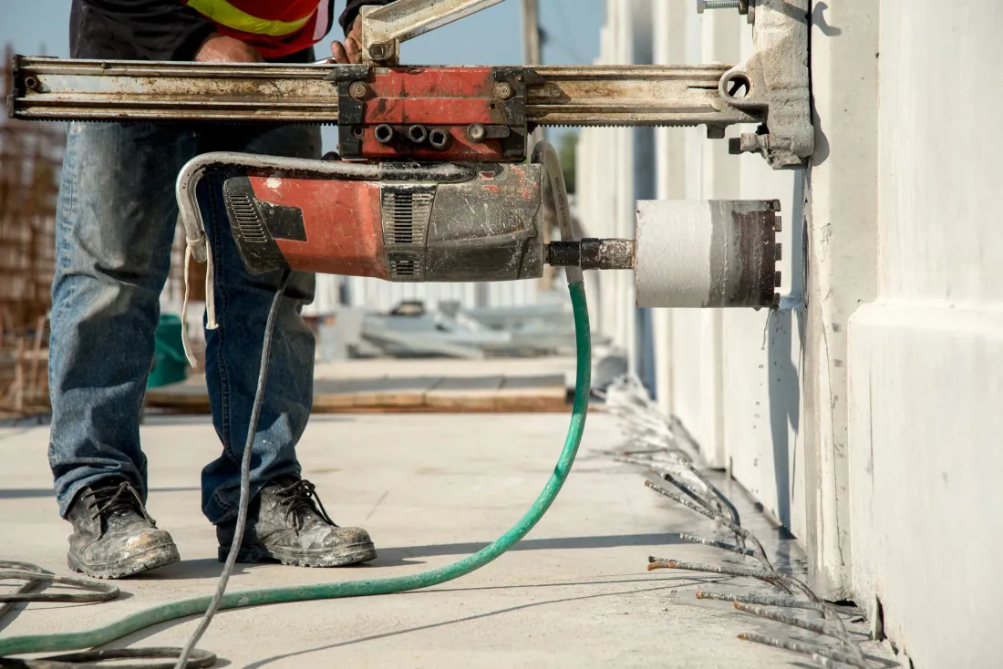 Technicien LES3 réalisant un carottage à l'eau dans un mur en béton
